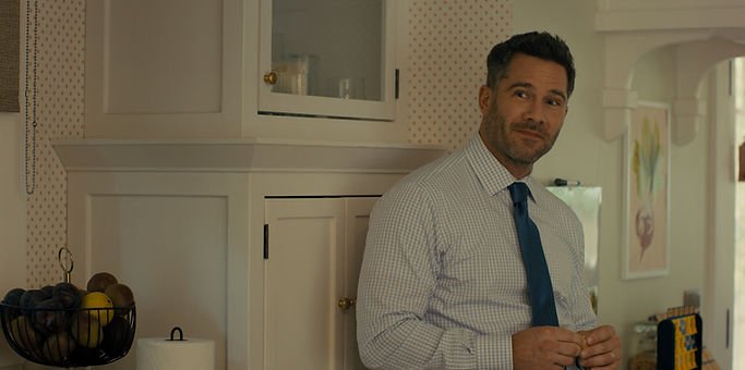 Luke Macfarlane in 'Platonic,' leaning against a cabinet.