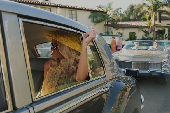 Kristen Wiig as Maxine in 'Palm Royale' Season 2 sat in a car with her arm resting on its open window and hand out.