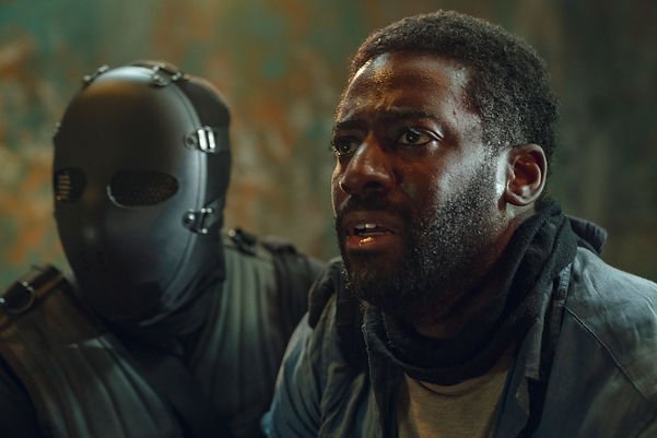 Ashley Thomas as Dr. Alex looking shocked with a masked agent in Episode 2 of Hostage