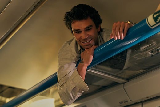 KJ Apa as Jack lying on a train's luggage rack with his head peeking over in Prime Video's The Map That Leads To You.