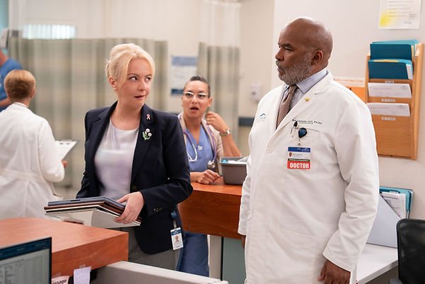 Wendi McLendon-Covey as Joyce and David Alan Grier as Dr. Ron looking at each other at a nurse's station in St. Denis Medical  "Get Me In The Pod, Brother" Episode 203.