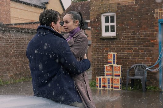 Sofia Carson and Corey Mylchreest holding on to each other in the Oxford rain.