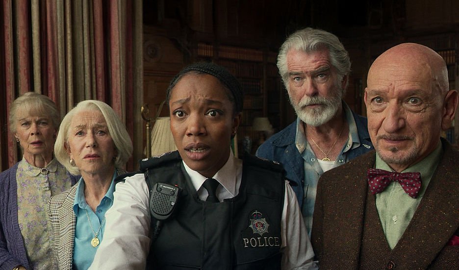 (L-R) Celia Imrie as Joyce, Helen Mirren as Elizabeth, Naomi Ackie as Donna, Pierce Brosnan as Ron, and Ben Kingsley as Ibrahim with shocked looks on their faces.