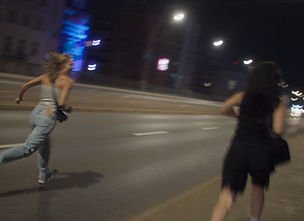 Two young women running down the street in Erupcja