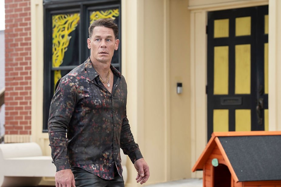 John Cena as Christopher Smith/Peacemaker looking surprised while walking on a street in Peacemaker Season 2