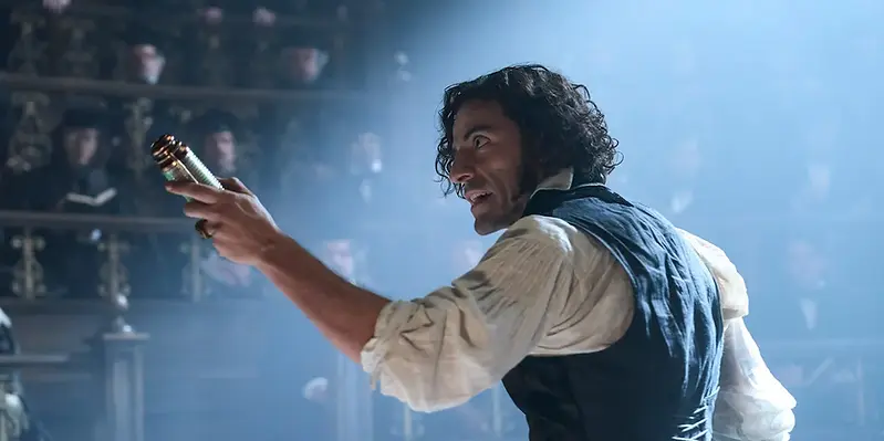 A man demonstrates to a crowd, an object held in his outstretched arm