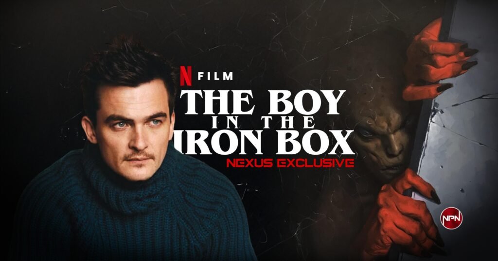 Rupert Friend in a dark blue sweater looking at the distance. The Boy In The Iron Box artwork is on the right.