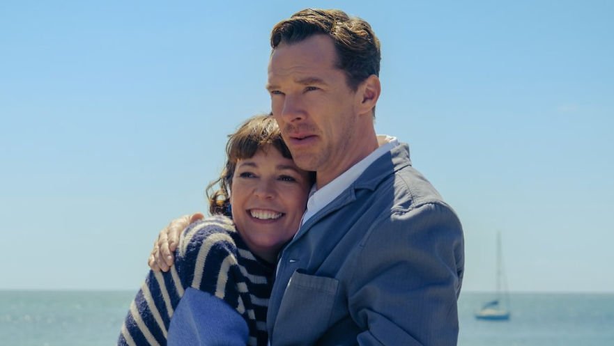 Olivia Colman and Benedict Cumberbatch embrace in front of an ocean backdrop