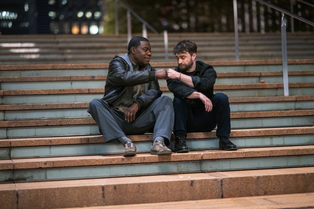 Tracy Morgan as Reggie Dinkins and Daniel Radcliffe as Arthur Tobin fist bumping on the Lincoln Center steps in The Fall and Rise of Reggie Dinkins