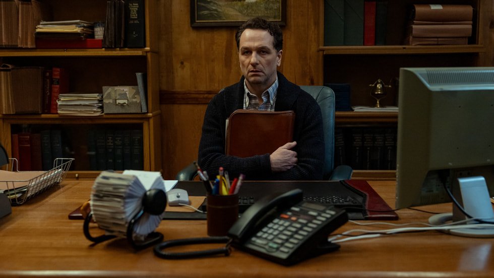 Matthew Rhys sitting behind a desk clutching a leather briefcase to his chest in 'Widows Bay'