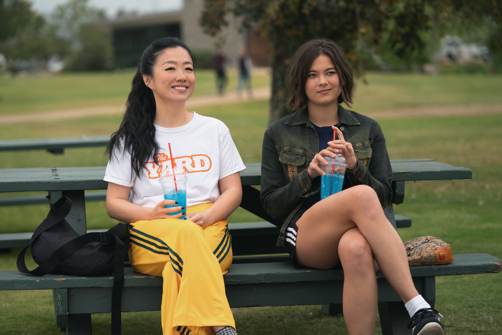 Sherry Cola as Maya and Lukita Maxwell as Alice sat on a park bench together in Shrinking Season 3
